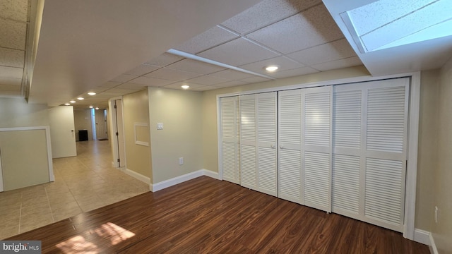 below grade area with a paneled ceiling, baseboards, wood finished floors, and recessed lighting