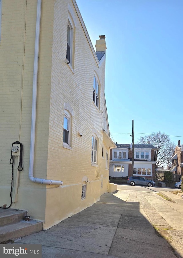 view of property exterior with brick siding and a chimney