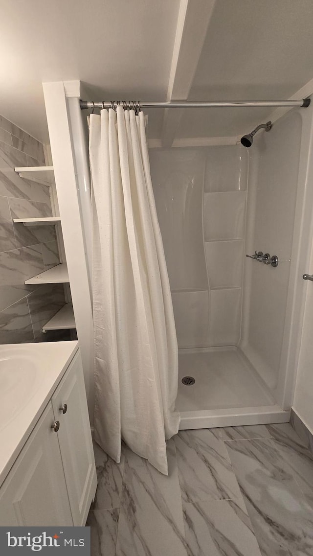 full bathroom with marble finish floor, a shower stall, and vanity