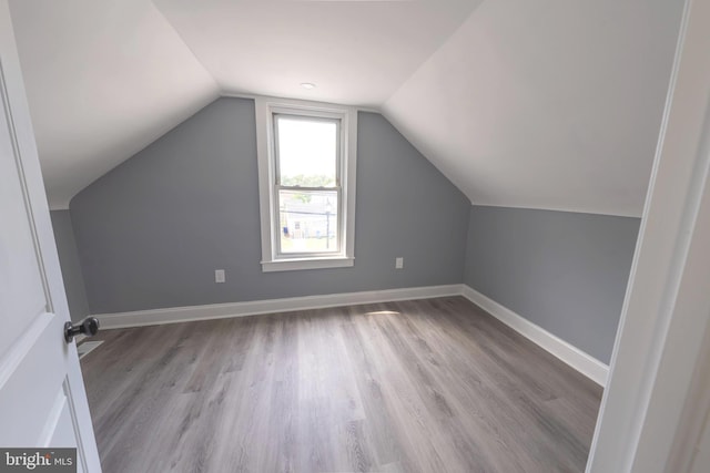 additional living space featuring light wood-type flooring and vaulted ceiling