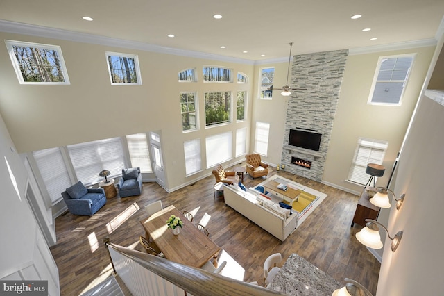 living room featuring dark wood-type flooring, crown molding, and a stone fireplace