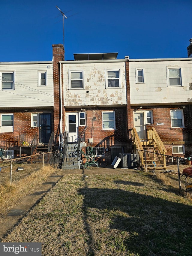 rear view of house with central AC unit and a yard