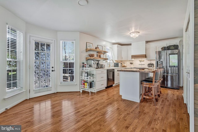 kitchen with open shelves, custom range hood, stainless steel refrigerator with ice dispenser, white cabinetry, and dishwashing machine