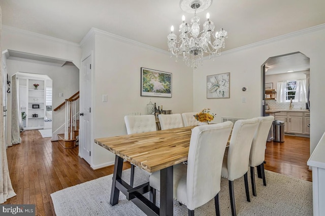 dining area with hardwood / wood-style flooring, arched walkways, ornamental molding, and stairs