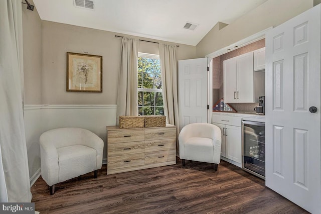 living area with dark wood finished floors, beverage cooler, visible vents, and lofted ceiling
