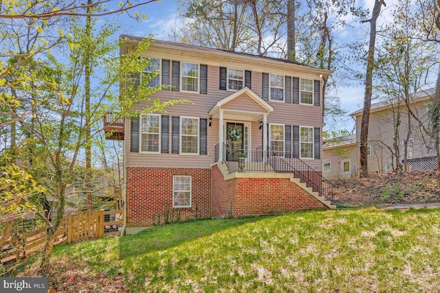 colonial inspired home with fence, a front lawn, and stairs