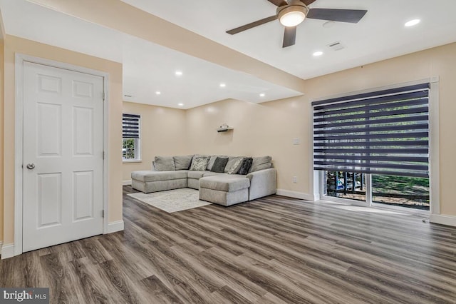 living area featuring baseboards, a ceiling fan, wood finished floors, and a healthy amount of sunlight