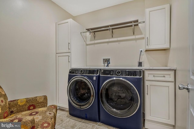 clothes washing area featuring washer and dryer, light tile patterned floors, and cabinet space