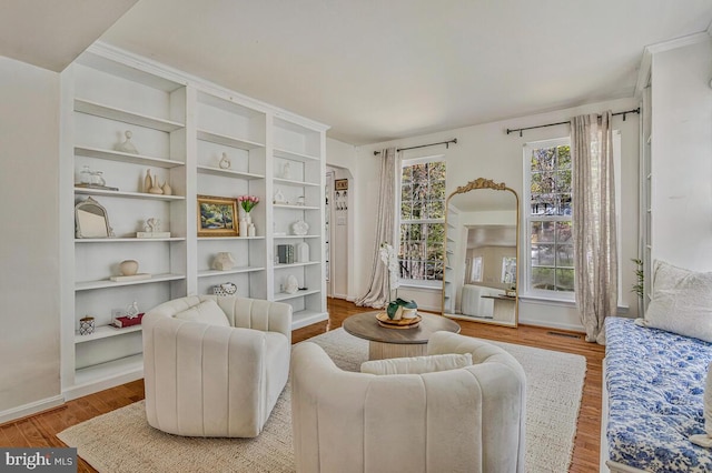 living area with wood finished floors, visible vents, and baseboards