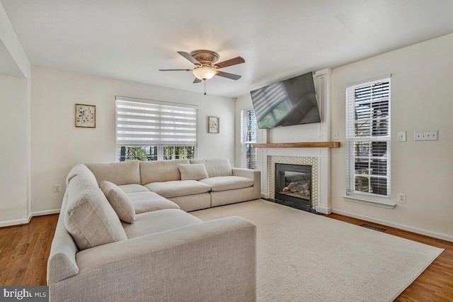 living area with ceiling fan, baseboards, wood finished floors, and visible vents