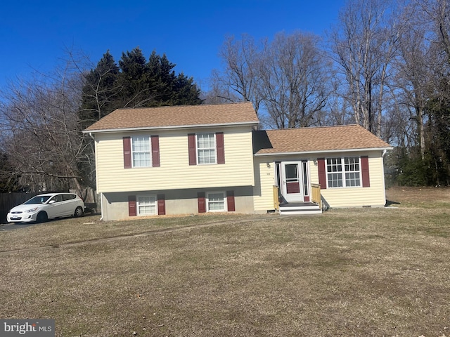 tri-level home with a shingled roof and a front lawn