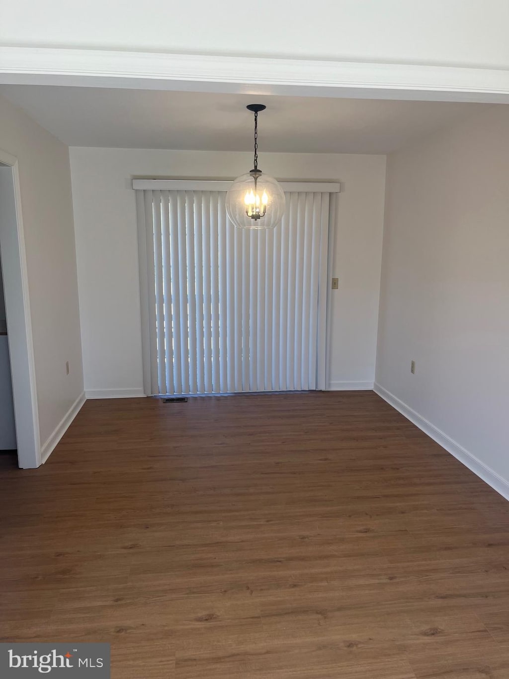 empty room with dark hardwood / wood-style floors and a notable chandelier