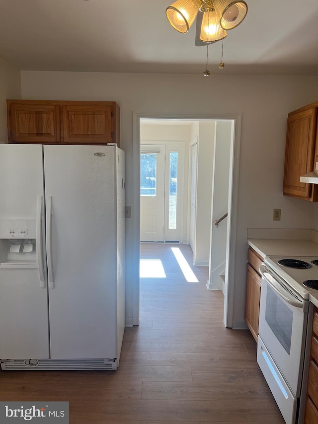 kitchen with white appliances, light hardwood / wood-style flooring, and extractor fan