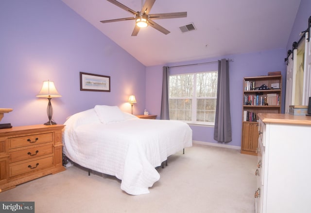 bedroom featuring light carpet, a barn door, vaulted ceiling, and visible vents