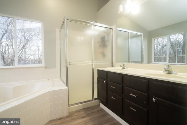 full bathroom with a stall shower, vaulted ceiling, a sink, and wood finished floors