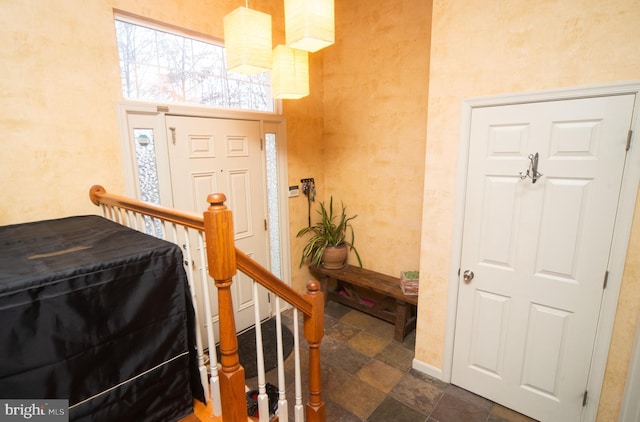 foyer featuring stone tile flooring and baseboards