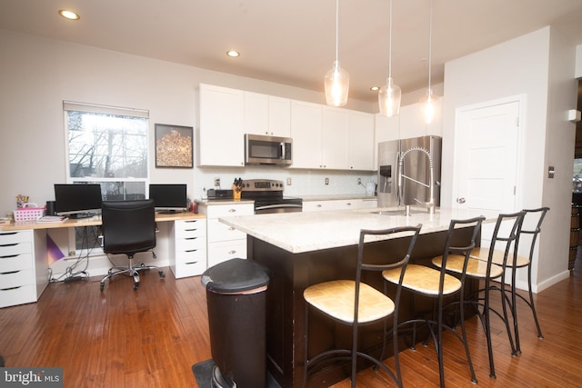 kitchen featuring stainless steel appliances, white cabinets, dark wood-style floors, and tasteful backsplash