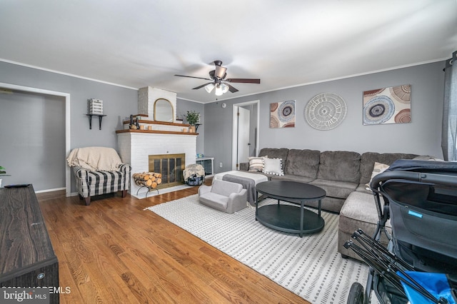 living room featuring crown molding, hardwood / wood-style flooring, a fireplace, and ceiling fan