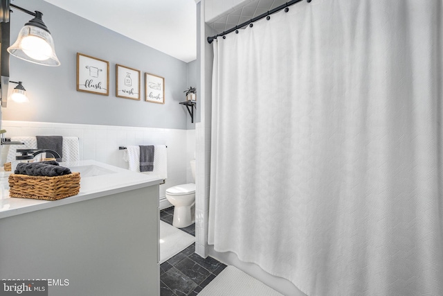 bathroom featuring vanity, tile walls, and toilet