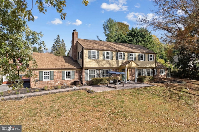 colonial home with a patio and a front lawn