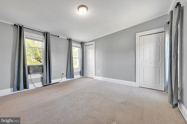unfurnished bedroom featuring carpet floors, baseboards, ornamental molding, and cooling unit
