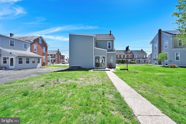 back of house featuring a residential view and a lawn