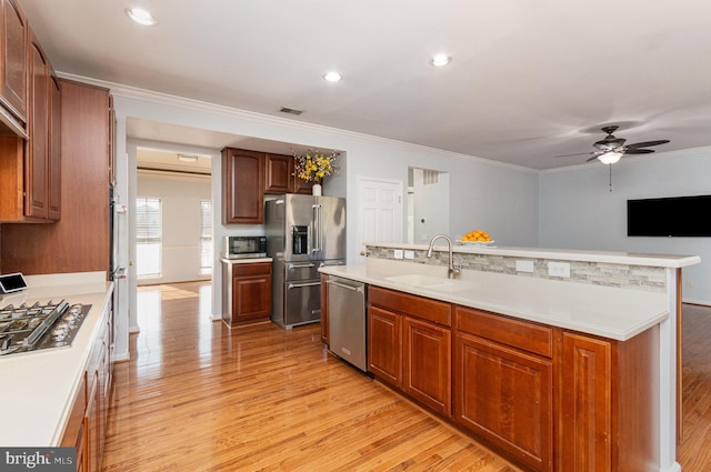 kitchen featuring appliances with stainless steel finishes, light wood-type flooring, light countertops, and a sink