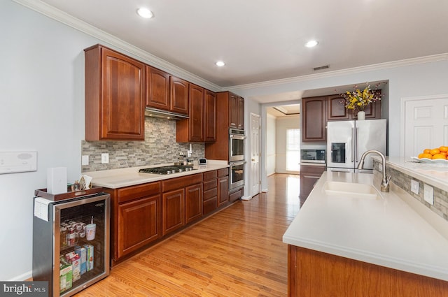 kitchen with wine cooler, stainless steel appliances, light countertops, visible vents, and a sink