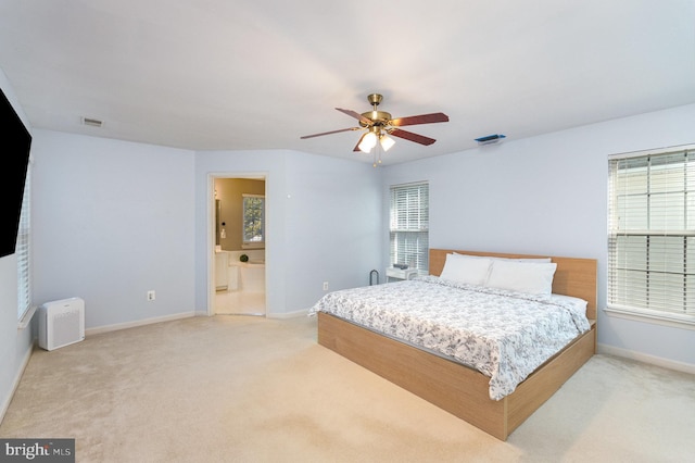 bedroom with ceiling fan, connected bathroom, light colored carpet, visible vents, and baseboards