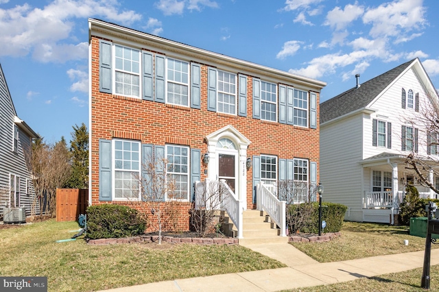 colonial house featuring brick siding, central AC, and a front lawn