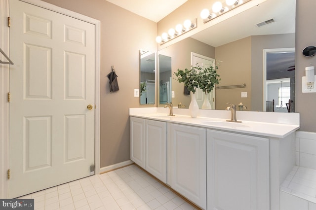 bathroom featuring double vanity, baseboards, visible vents, tile patterned flooring, and a sink