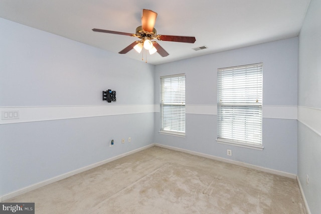 empty room with visible vents, ceiling fan, light carpet, and baseboards