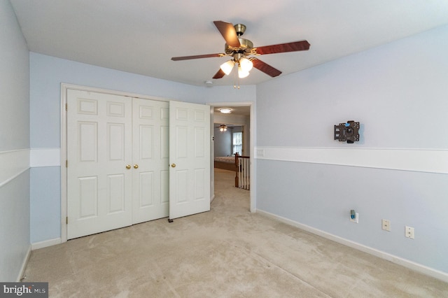 unfurnished bedroom featuring light carpet, ceiling fan, baseboards, and a closet