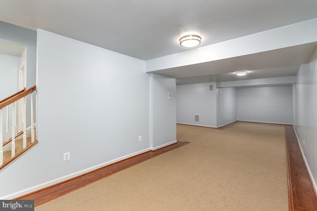 finished basement featuring light carpet, stairs, and baseboards