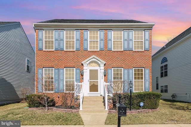 colonial home with brick siding and a lawn