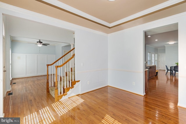 empty room featuring wood-type flooring, visible vents, crown molding, and stairs