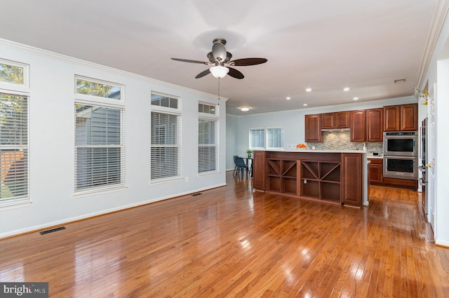 kitchen featuring stainless steel double oven, a kitchen island, visible vents, light countertops, and decorative backsplash