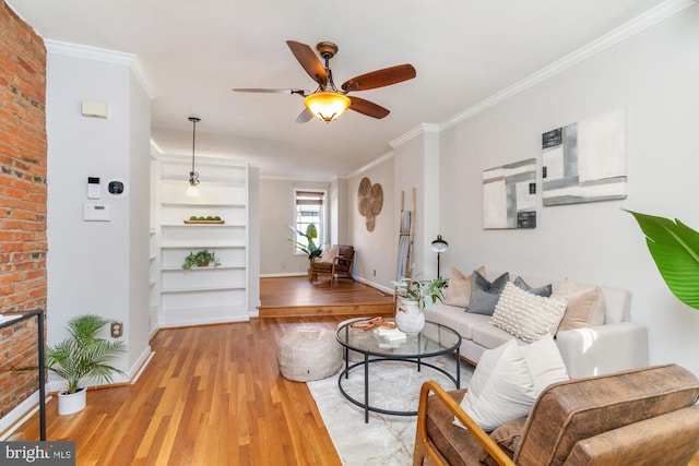 living area featuring ornamental molding, baseboards, ceiling fan, and light wood finished floors