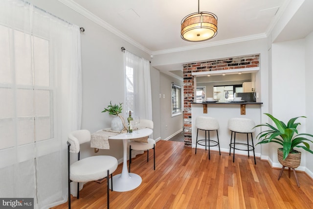 dining area featuring ornamental molding, baseboards, and light wood finished floors