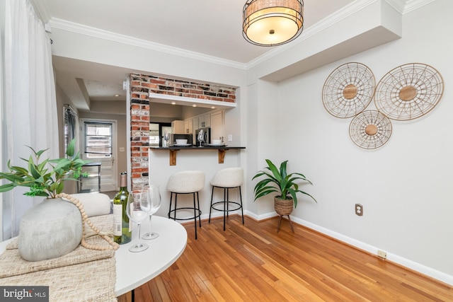 interior space with a peninsula, light wood finished floors, baseboards, and crown molding