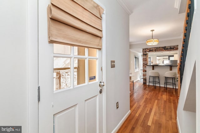 interior space featuring baseboards, wood finished floors, and crown molding