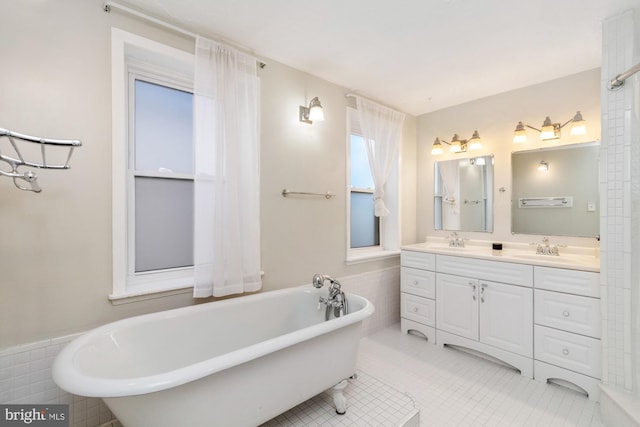 full bathroom featuring a freestanding bath, double vanity, a sink, and tile patterned floors