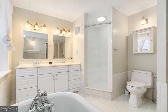 bathroom featuring tile walls, toilet, wainscoting, a sink, and tile patterned flooring