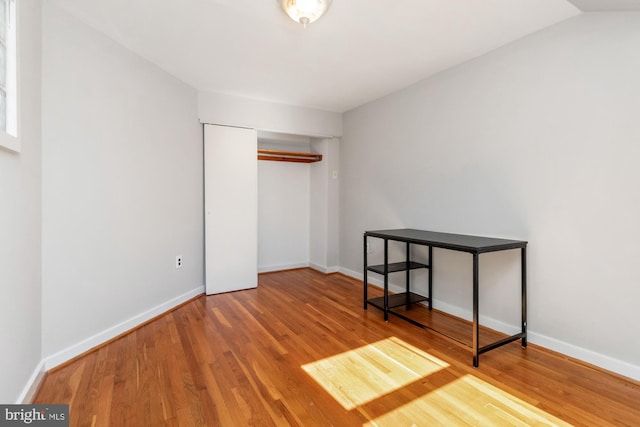 unfurnished bedroom with a closet, baseboards, and wood finished floors