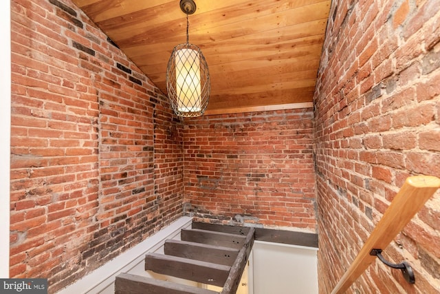 interior space featuring lofted ceiling, wood ceiling, and brick wall