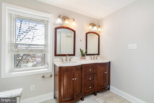 bathroom featuring double vanity, baseboards, and a sink