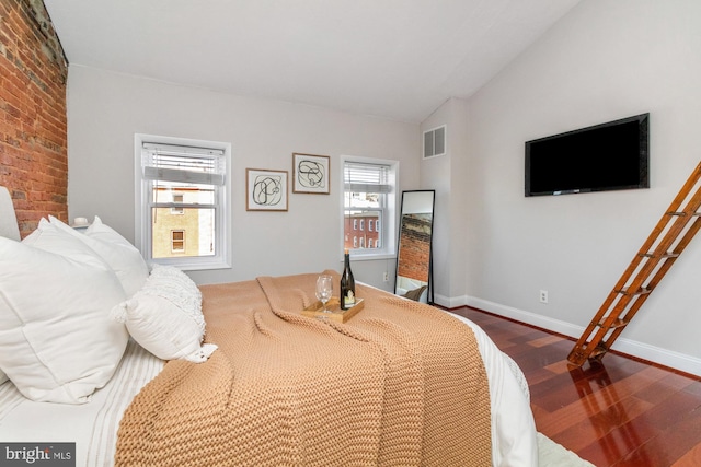 bedroom with dark wood-style flooring, visible vents, vaulted ceiling, and baseboards