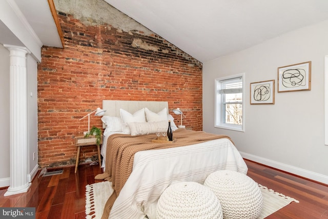 bedroom featuring decorative columns, baseboards, dark wood-style floors, brick wall, and vaulted ceiling