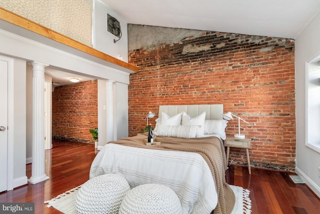 bedroom with lofted ceiling, ornate columns, brick wall, and dark wood-style flooring