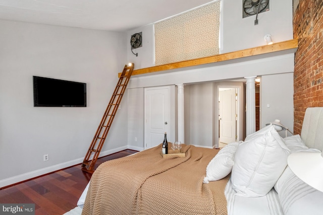 bedroom featuring dark wood-style floors, ornate columns, and baseboards